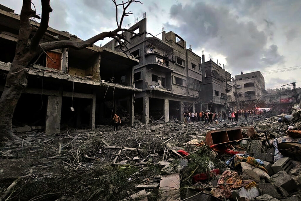 Image depicts a ruined pair of buildings in Gaza. Rubble litters the ground in the forefront of the image.